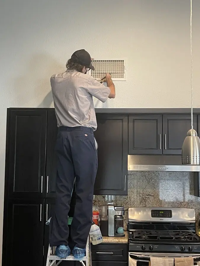 Technician inspecting an air vent during HVAC service in Alpharetta